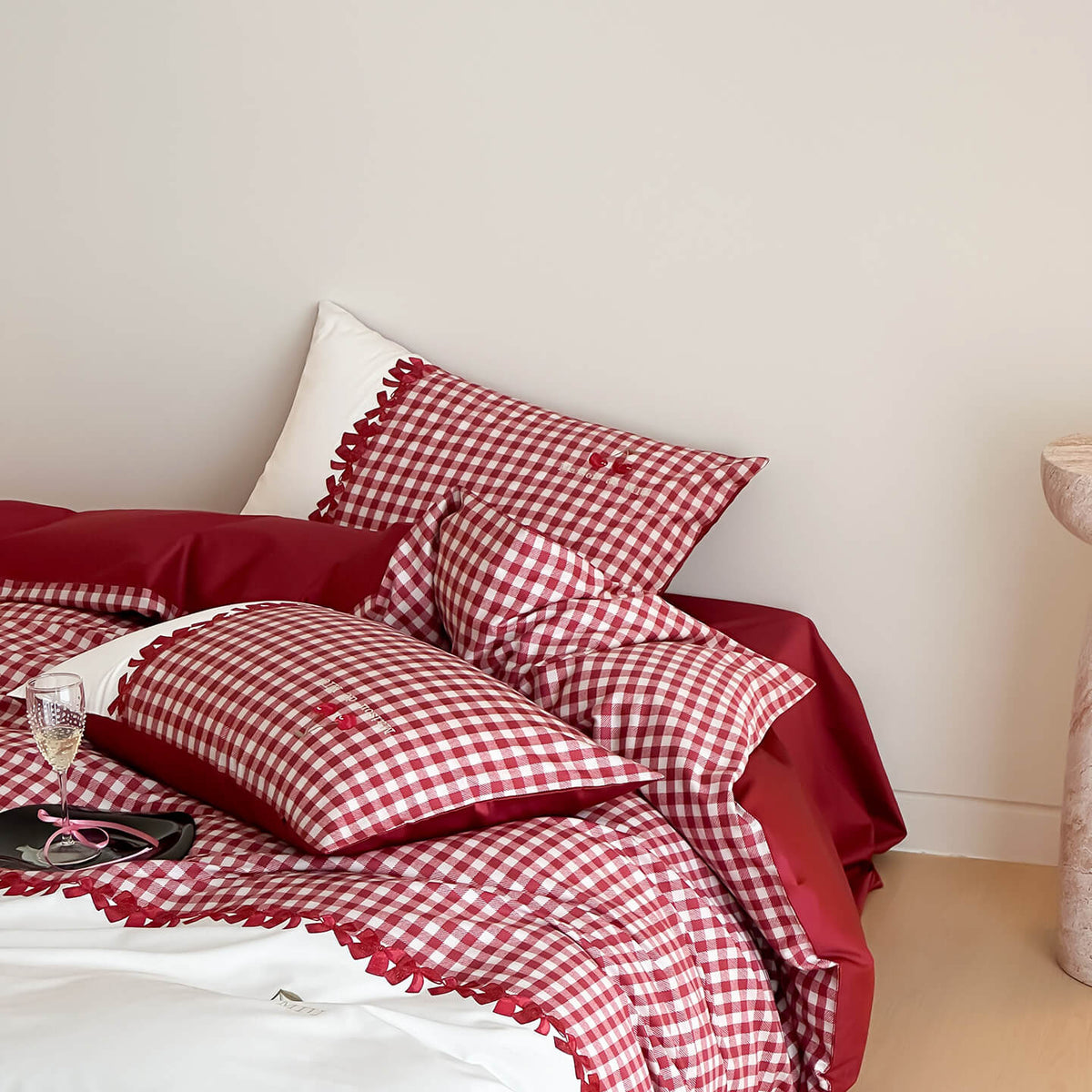 Red and white checkered bedding set on a bed with a plain wall background