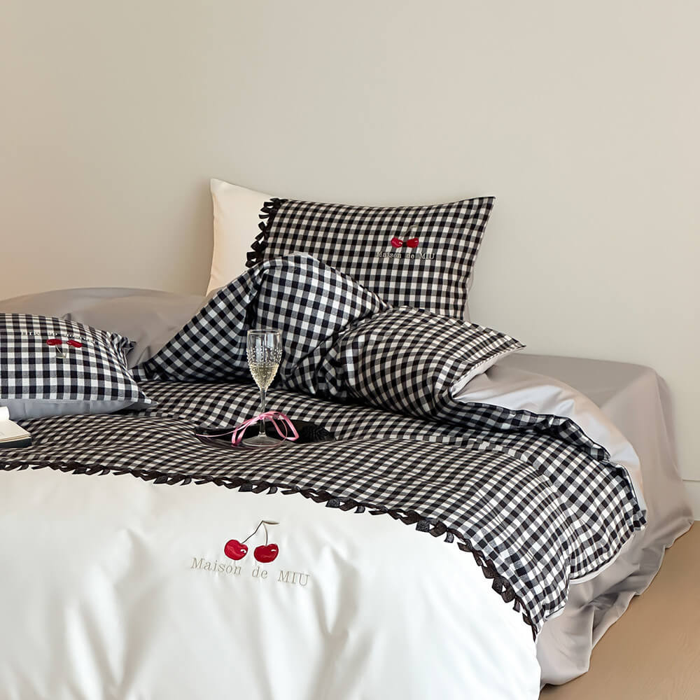 Black and white checkered bedding set with cherry design on a bed.