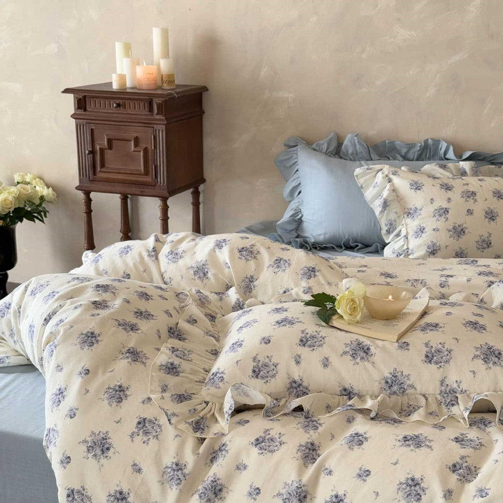 Full shot of a shabby chic bedroom featuring the Dusty Blue Floral Bedding set, with a ruffled duvet cover and matching pillowcases, creating a cozy and romantic atmosphere.