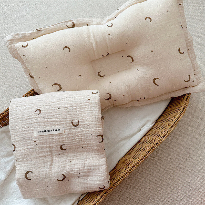 Folded brown moon and star muslin blanket and matching quilted pillow set in a wicker basket