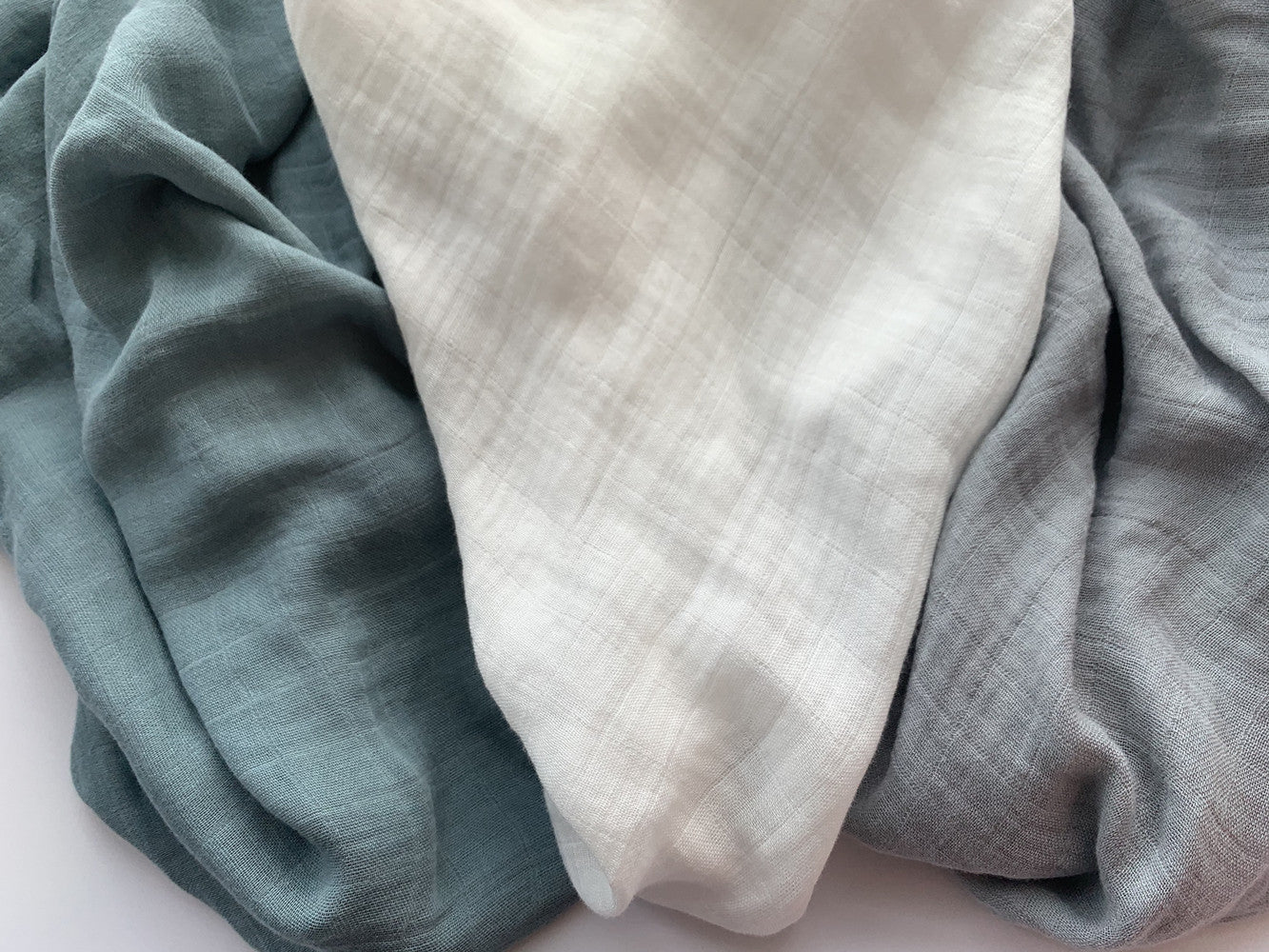 Close-up detail of the lightweight, soft bamboo muslin fabric in teal, off-white, and slate gray, highlighting the crinkle gauze texture.
