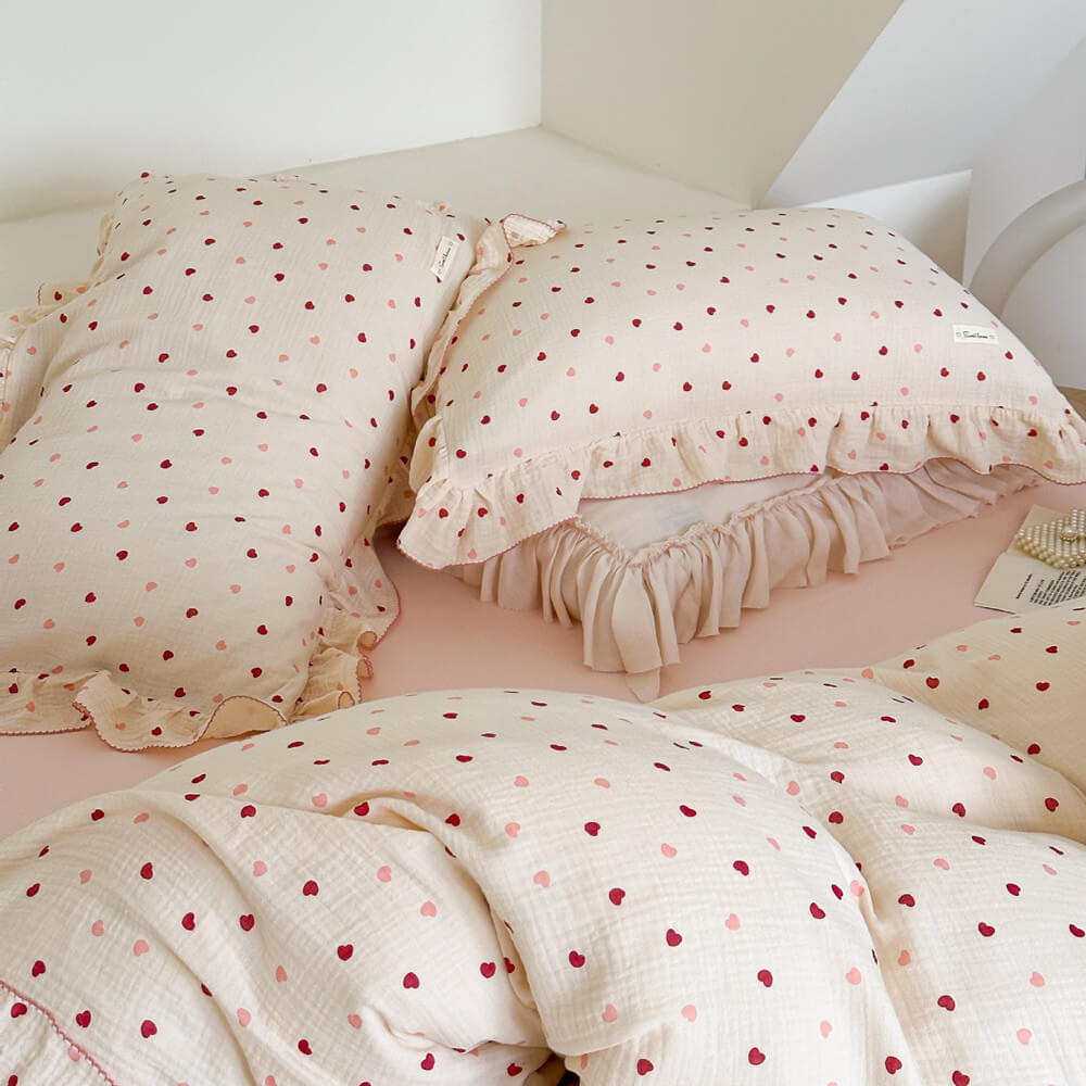Pink heart duvet cover set in a bedroom with ruffled pillows and a matching cotton muslin duvet