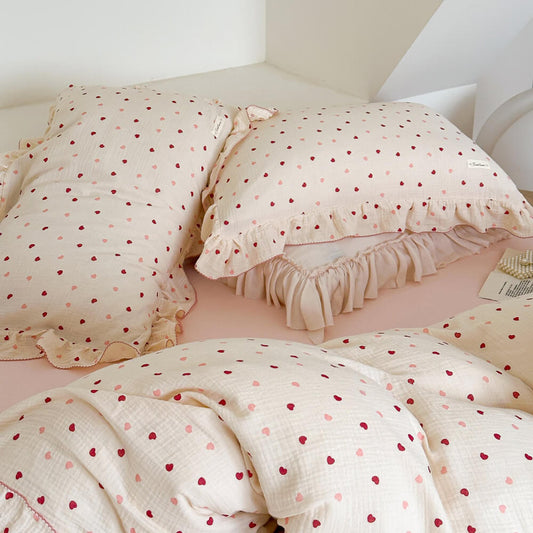 Pink heart duvet cover set in a bedroom with ruffled pillows and a matching cotton muslin duvet