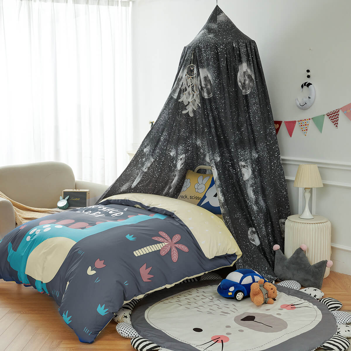 Black Galaxy Kids Bed Canopy for a single bed, showing the moon and star print with a dinosaur comforter and lion mat