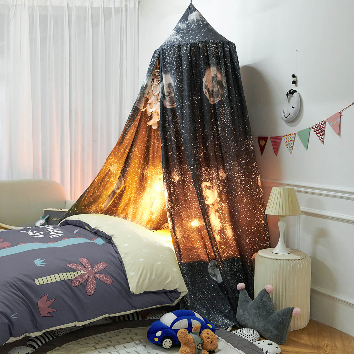 Black Galaxy Kids Bed Canopy with Moon & Stars Design over a bed, with a warm light inside creating a glowing, cosmic effect