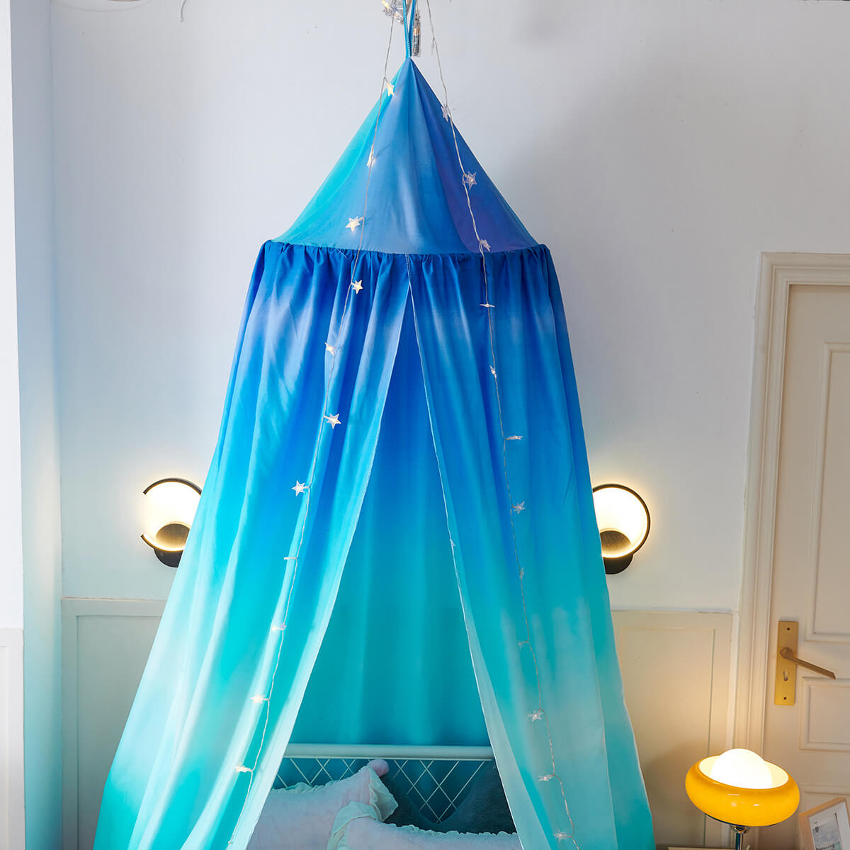 Close-up of a blue gradient kids' bed canopy, decorated with small star string lights.