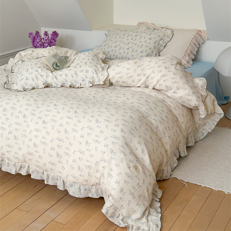 A full view of a modern bedroom with a queen-size bed, showcasing a white cotton gauze duvet cover set with a blue cat print and ruffled edges