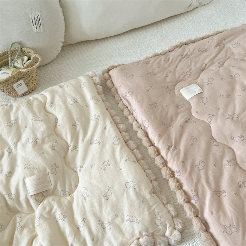 Two cotton comforter with bunny patterns on a light surface.