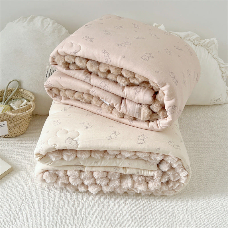 Folded kids cotton comforter with bunnypatterns on a white surface
