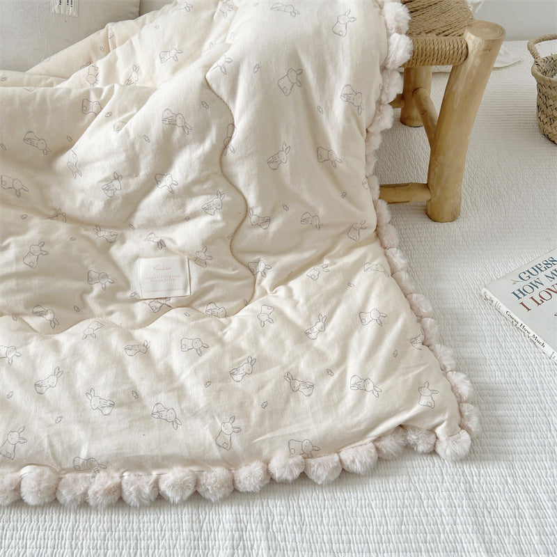 beige textured blanket with bunny patterns on a light wooden floor.