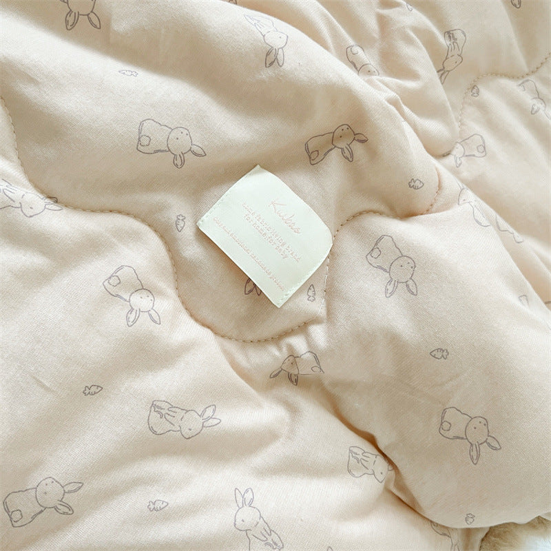 Beige quilt with bunny pattern and a white square on top