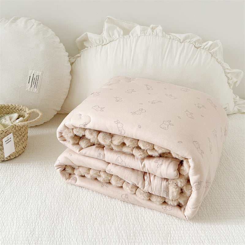 Folded baby quilt with soft texture on a white surface