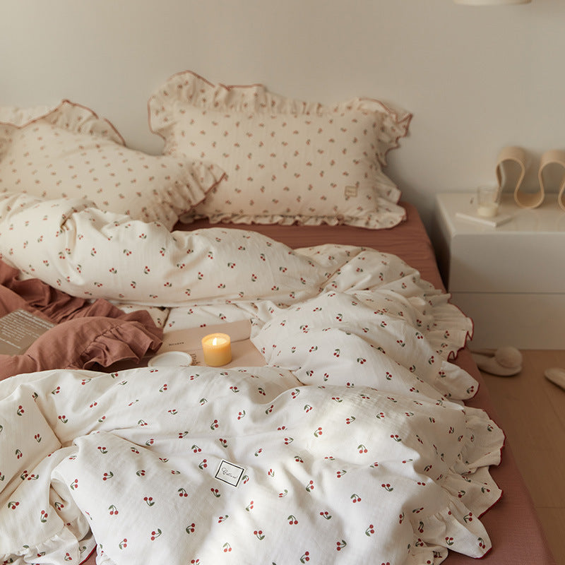 soft cotton muslin bedding set with a cherry print and ruffle trim, including a duvet cover and pillowcases, displayed on a bed.