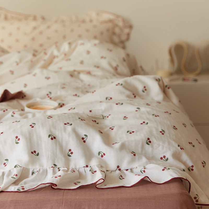 A detailed close-up shot of the ruffle and red piping on the cherry-print cotton muslin bedding set.