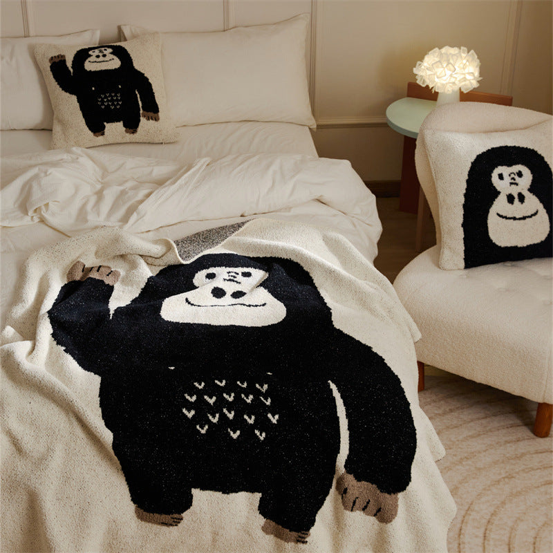 A black and white chimpanzee face design on a soft fleece throw blanket with a matching pillowcase on a bed.