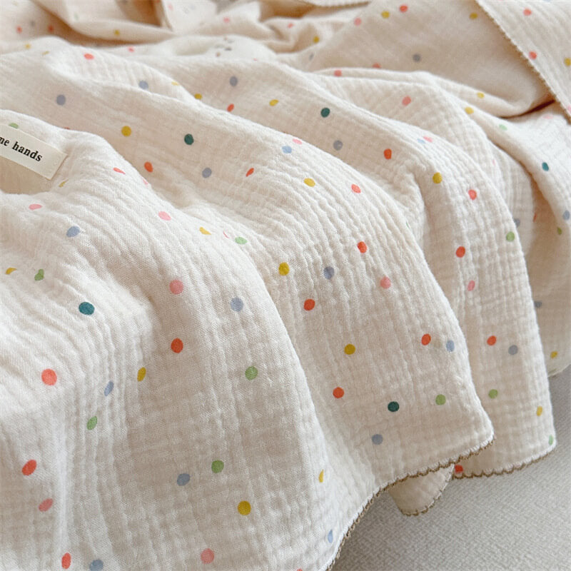 A side shot of the Colorful Dot muslin blanket, emphasizing its lightweight, breathable fabric and its colorful dots on a quilted surface.