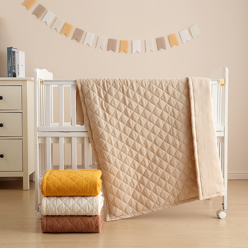 Soft cotton muslin baby quilt displayed in crib with natural light