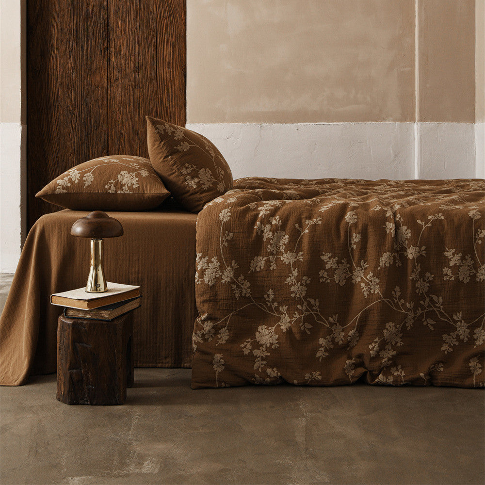 A full view of a bed styled with the brown floral cotton gauze bedding set, showcasing the full ensemble in a rustic bedroom setting.