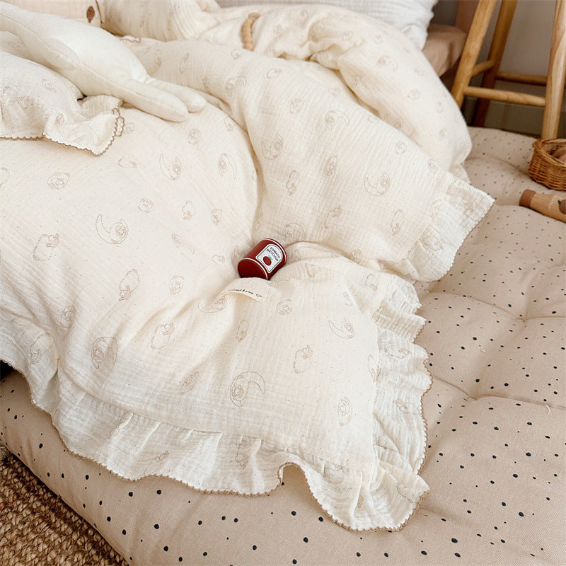 Lamb print ruffle duvet cover in cream cotton muslin, displayed on a dotted beige mattress, playful children’s decor