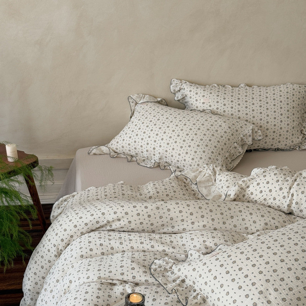 A full view of a bed styled with a cotton muslin duvet cover set, showing the ruffled pillowcases and duvet cover.