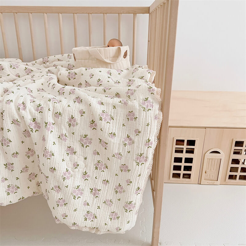 Lightweight muslin baby quilt with lace in toddler bed