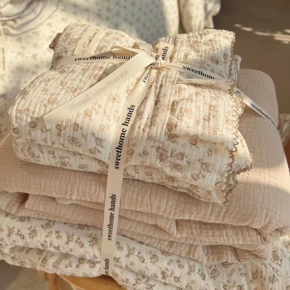 A folded camellia print cotton muslin duvet set, tied with a ribbon, showing the bedding ready for packaging