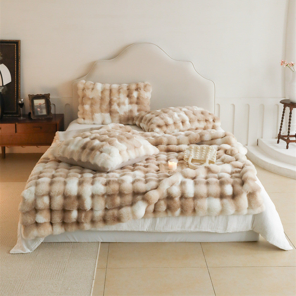 Soft dark brown fluffy faux rabbit fur throw blanket and pillows on a bed with a laptop
