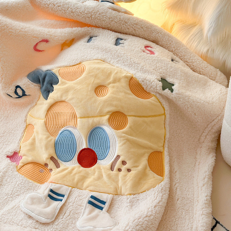 A detailed shot of the embroidered cheese character on a fleece and sherpa baby blanket.