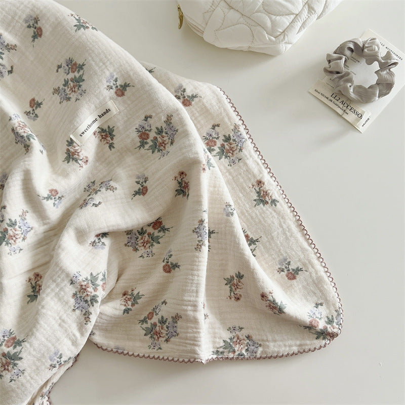 A close-up shot of a section of the Vintage Floral muslin toddler blanket, flat-laid on a padded surface. The image highlights the intricate floral pattern and the soft, crinkled texture of the muslin fabric.