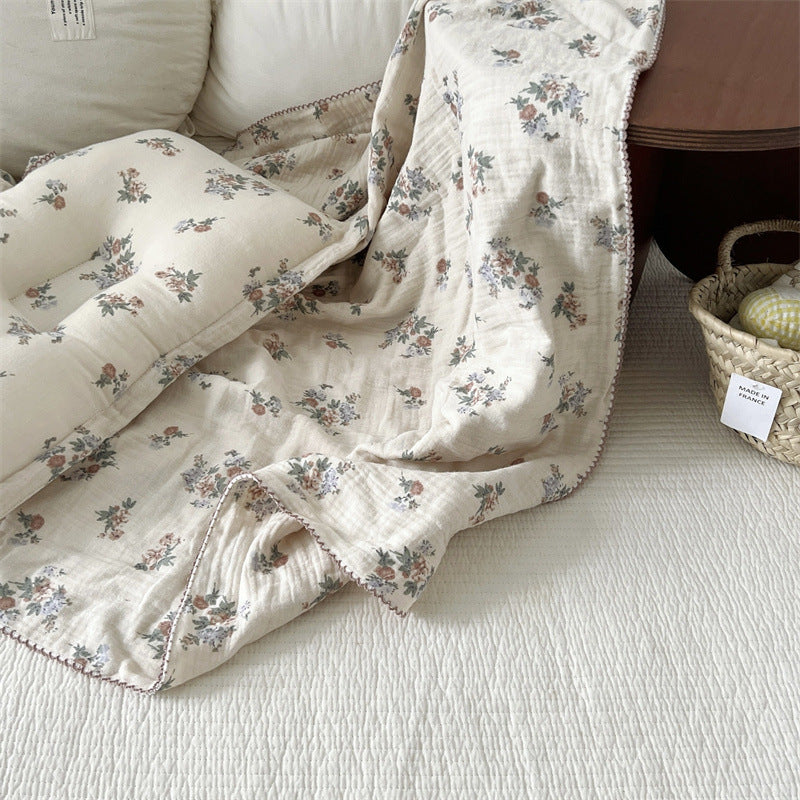 The Vintage Floral muslin toddler blanket and pillow set, elegantly draped over a couch, showing the intricate, timeless floral pattern.