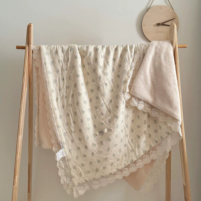 Blue floral ruffle blanket draped over a display rack in a nursery setting, emphasizing soft texture and lace details.