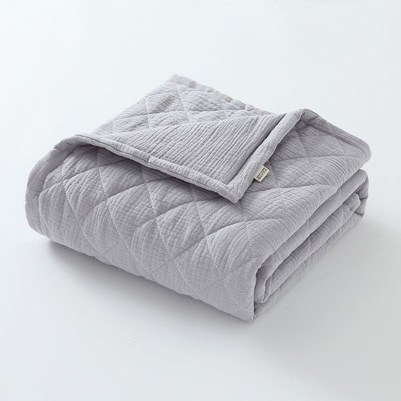 Folded grey cotton muslin baby quilt showing breathable and lightweight gauze texture