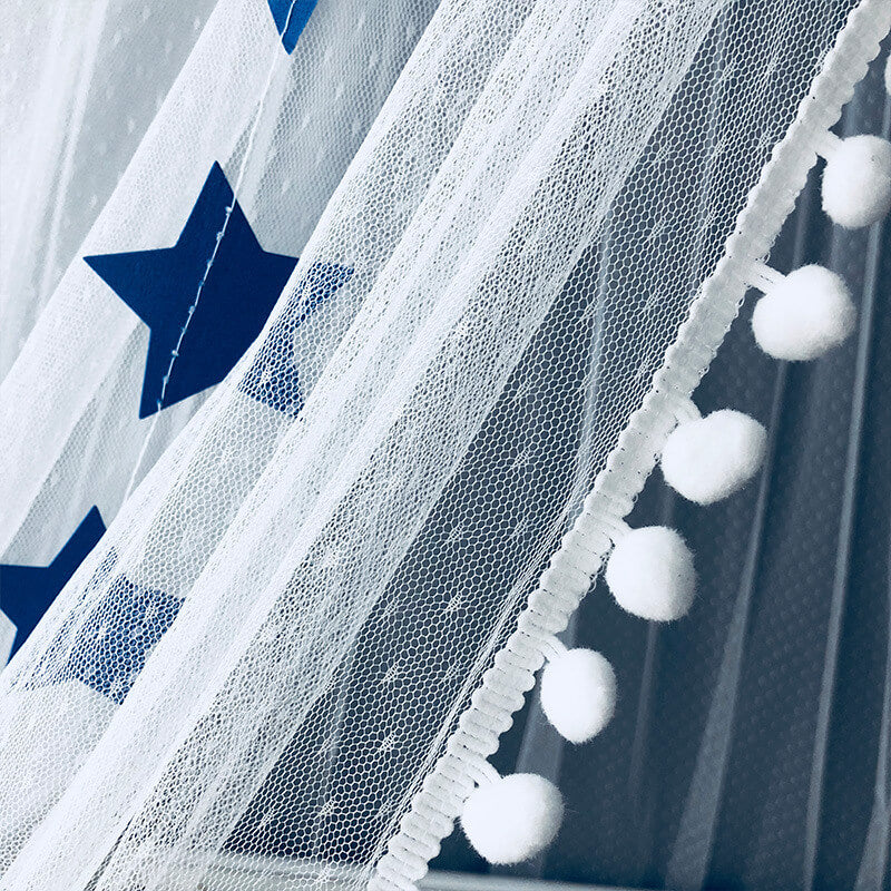 A detailed close-up shot of the white mesh fabric, blue star appliqués, and decorative white pom-pom trim on the hanging crib mosquito net canopy.