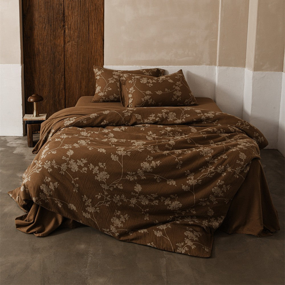 A lifestyle image of the brown floral cotton gauze bedding set on a bed with a wooden headboard, capturing a warm and natural aesthetic.