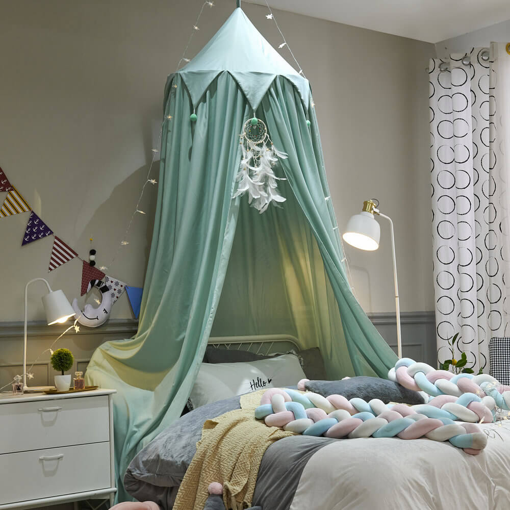 A mint green kids bed canopy with a triangular ruffle top and matching pom-poms, creating a cozy corner above a single bed.