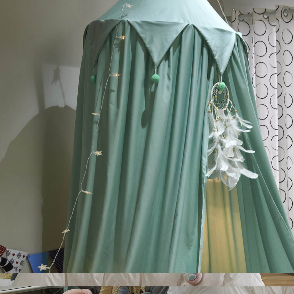 Close-up view of the mint green kids bed canopy, showing the falbala ruffle design, pom-poms, and a hanging dreamcatcher.