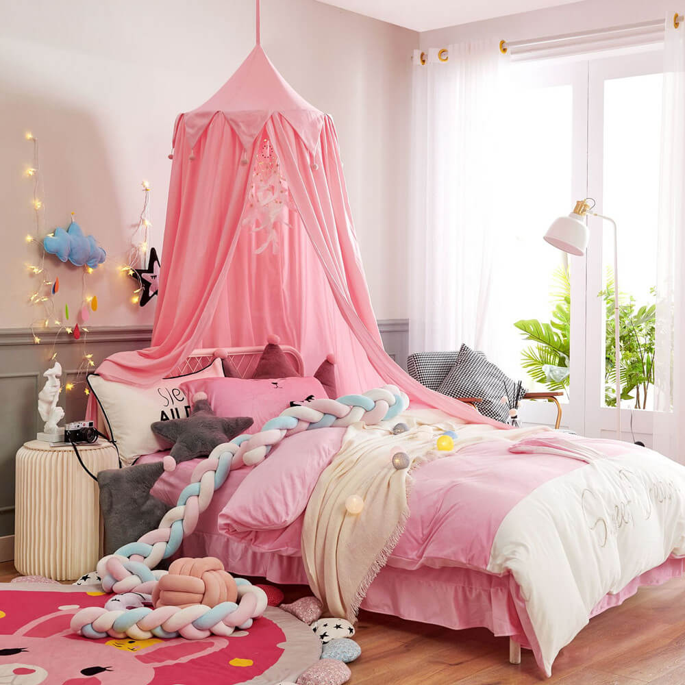 Vibrant pink kids bed canopy with falbala triangular ruffles and pom-poms, creating a princess-style bed for a girl's room.