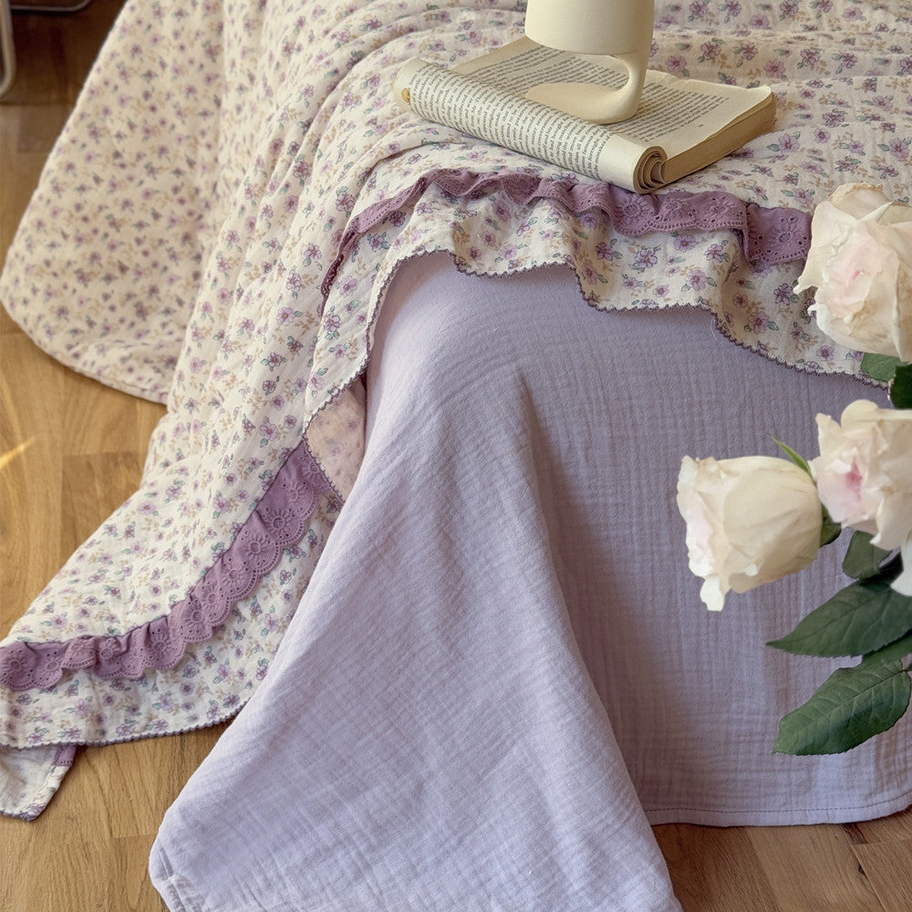 Lavender floral comforter with ruffled trim styled on lilac gauze sheet