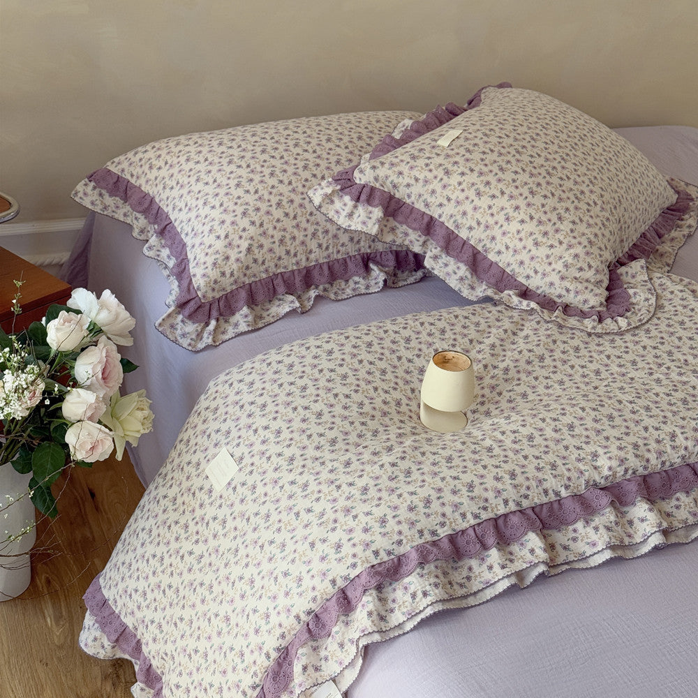 Stacked lavender floral comforter and matching pillows with candle decor