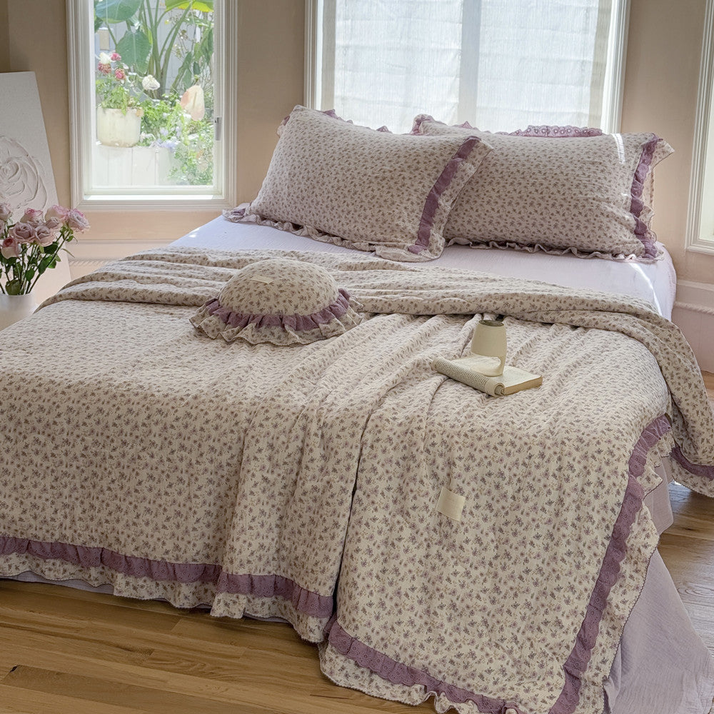 Girls’ room with lavender floral comforter and ruffled pillows in natural light