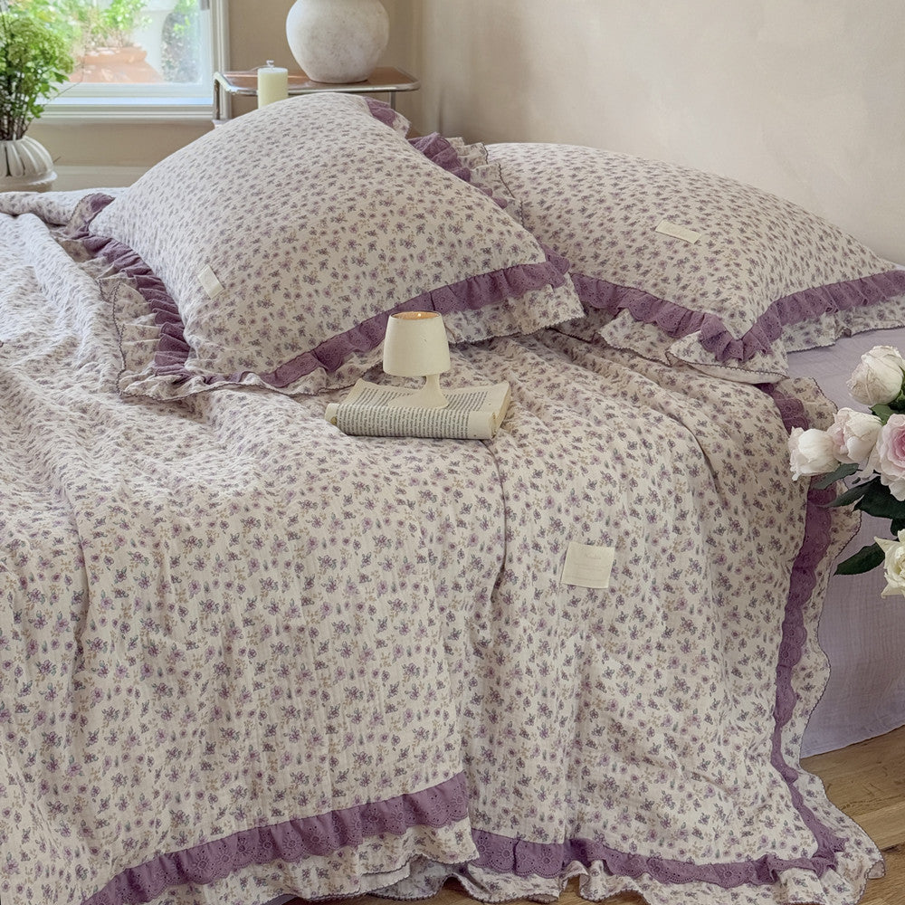 Lavender floral comforter on the bed, paired with soft white roses