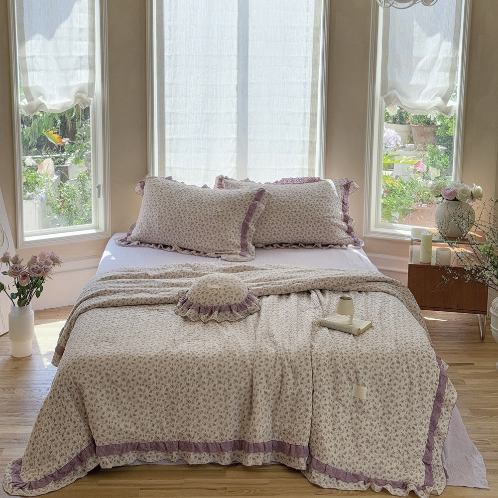 frontview of comforter and round pillow with double ruffles and floral pattern