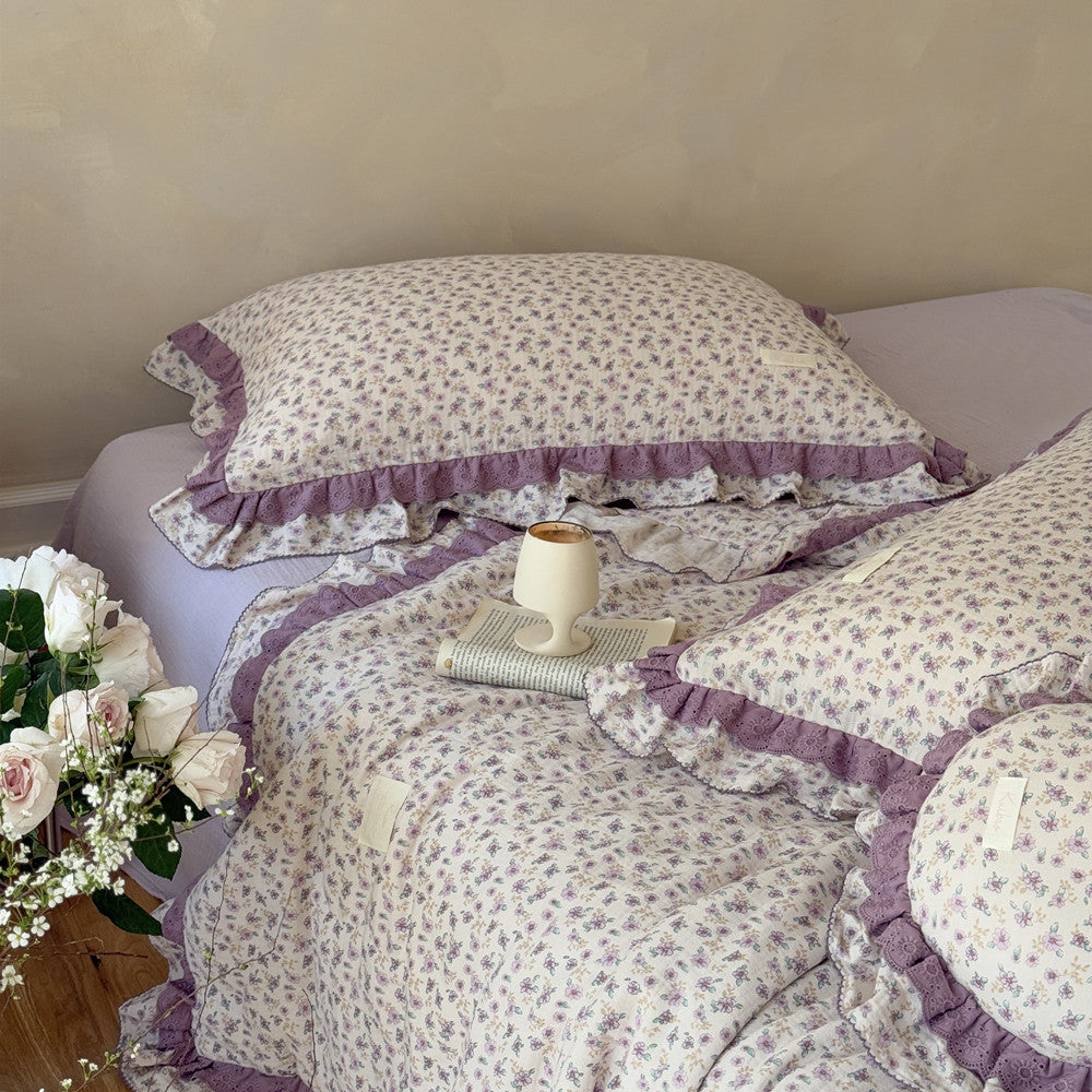 Fluffy floral comforter with purple ruffles and round pillow for kids’ room