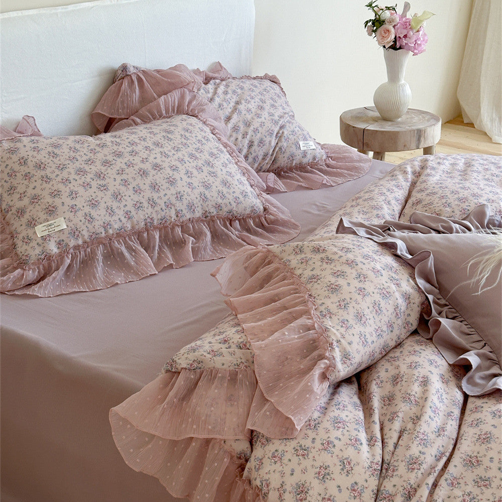 Angled view of the floral duvet cover and layered pillow shams from the Lavender Floral Bedding Set, showcasing the cascading mauve chiffon ruffled trim and the subtle floral print.