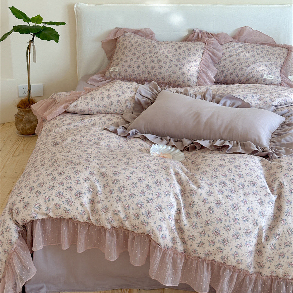 Full view of the Lavender Floral Gauze Bedding Set on a bed, showcasing the floral duvet cover and solid mauve lumbar pillow, all trimmed with romantic chiffon ruffles.