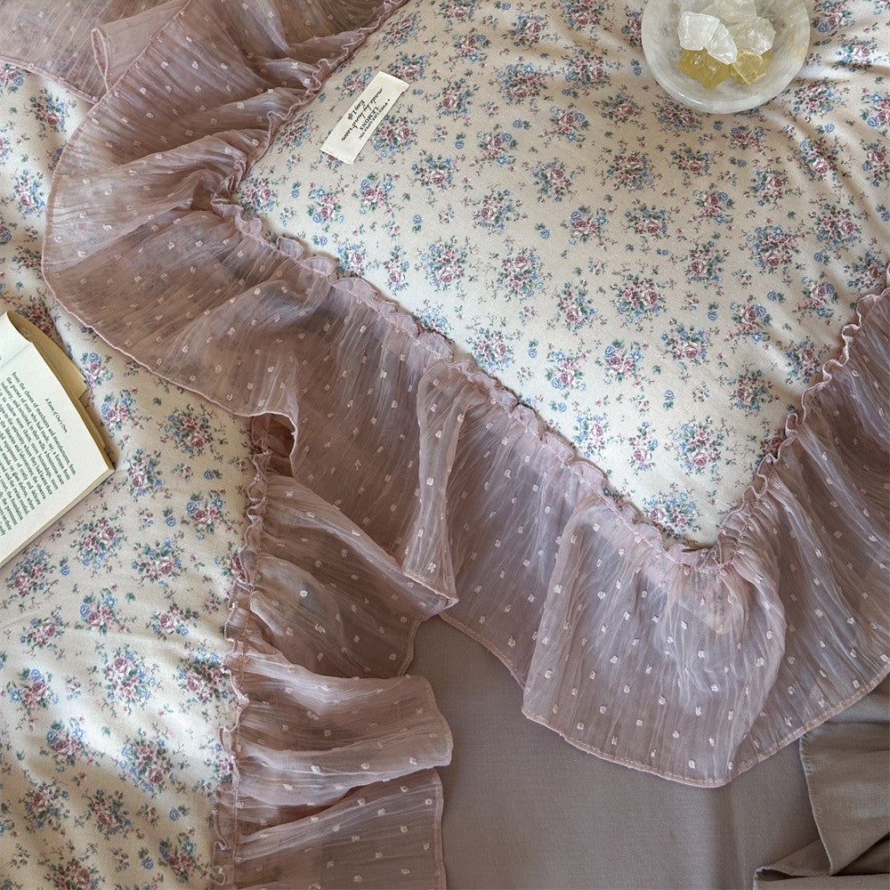 Detailed close-up of the Lavender Floral Gauze Bedding Set, emphasizing the delicate blue and pink floral pattern and the wide, sheer mauve chiffon ruffle with white polka dots.