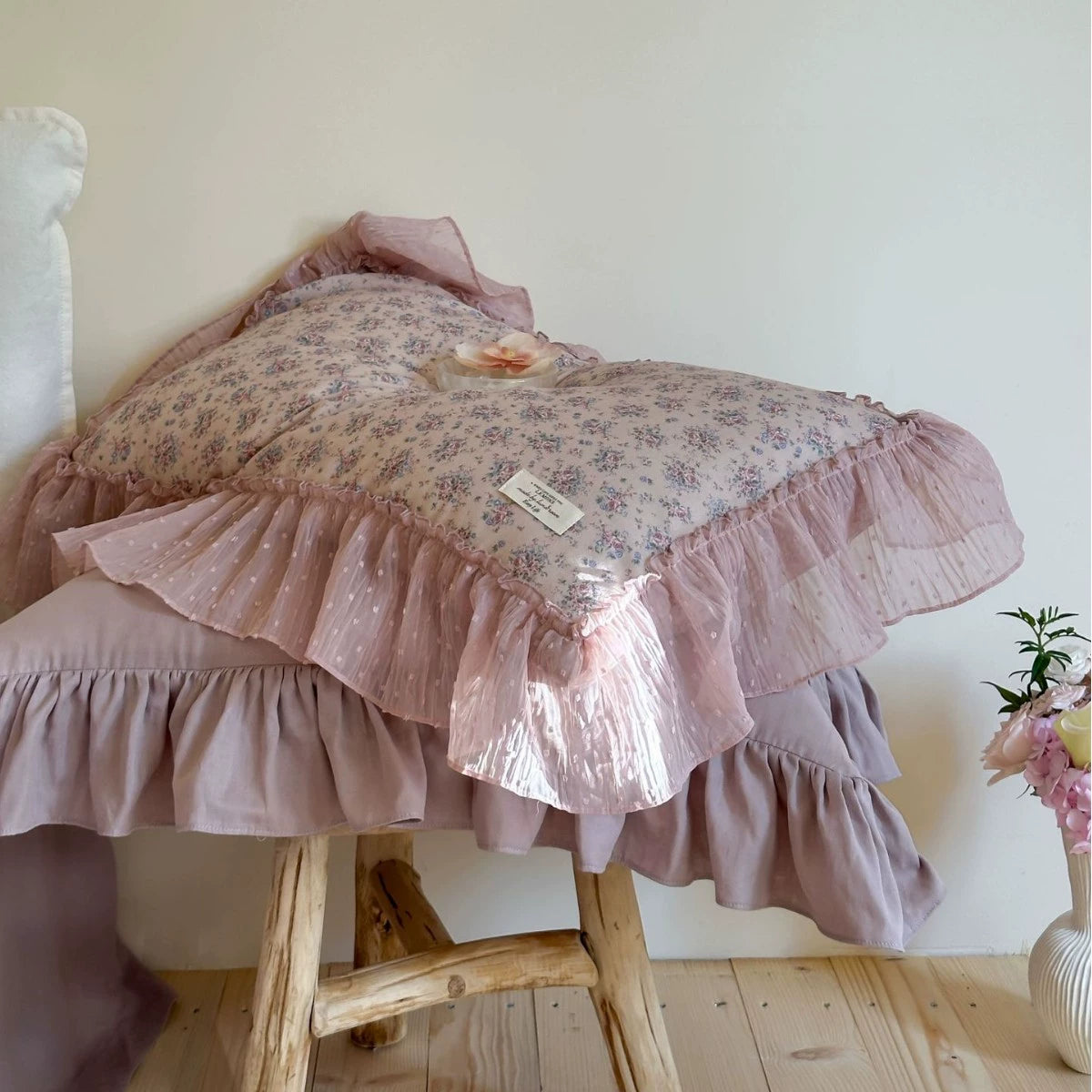 Lavender Floral pillowcase on a wooden stool, showcasing the distinct layers of the floral gauze, solid mauve fabric, and sheer ruffled chiffon trim.