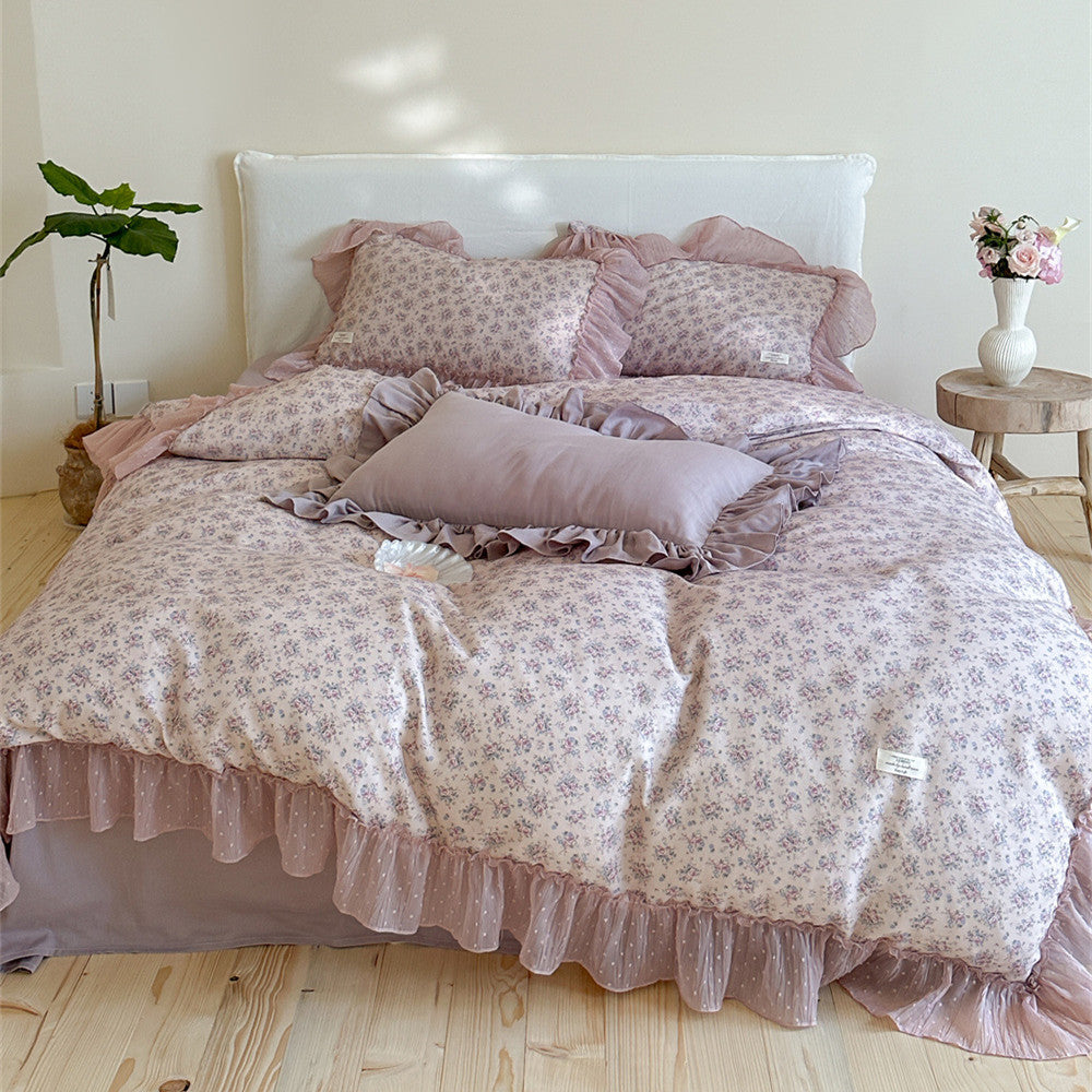 Full view of a Lavender Floral Gauze Bedding Set on a bed, featuring a floral duvet cover, solid mauve fitted sheet, and chiffon ruffled edges on all pieces, set in a bright, cozy bedroom.