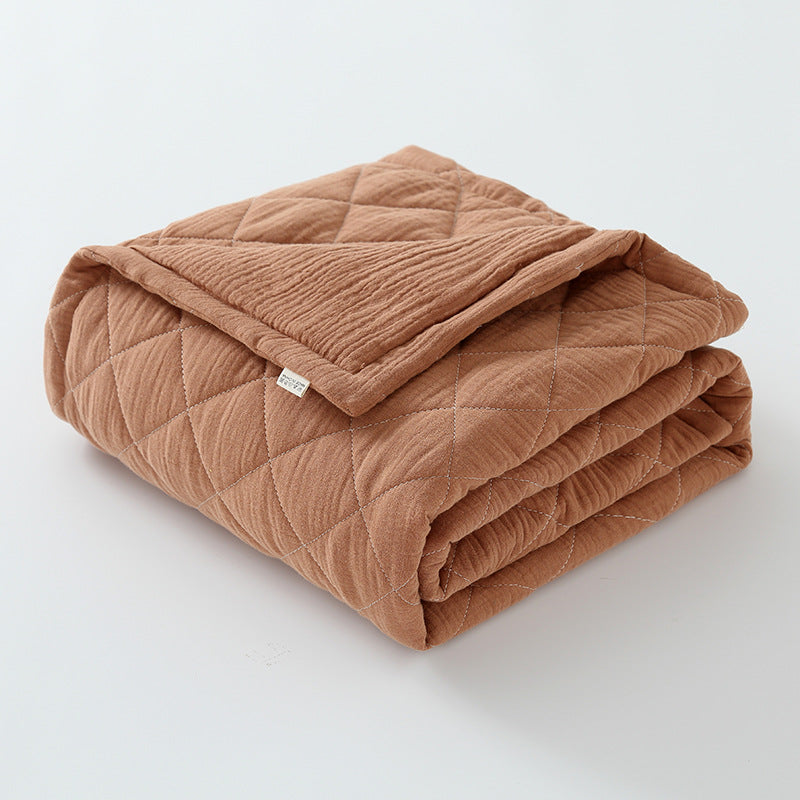 Chestnut brown cotton muslin baby quilt folded with warm earthy tone and quilted design