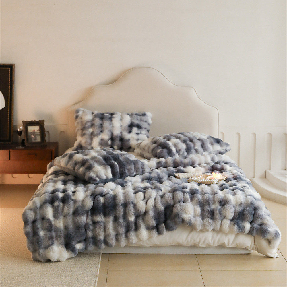 Luxury dary grey and white tie-dye patterned faux rabbit fur blanket and pillows on a bed